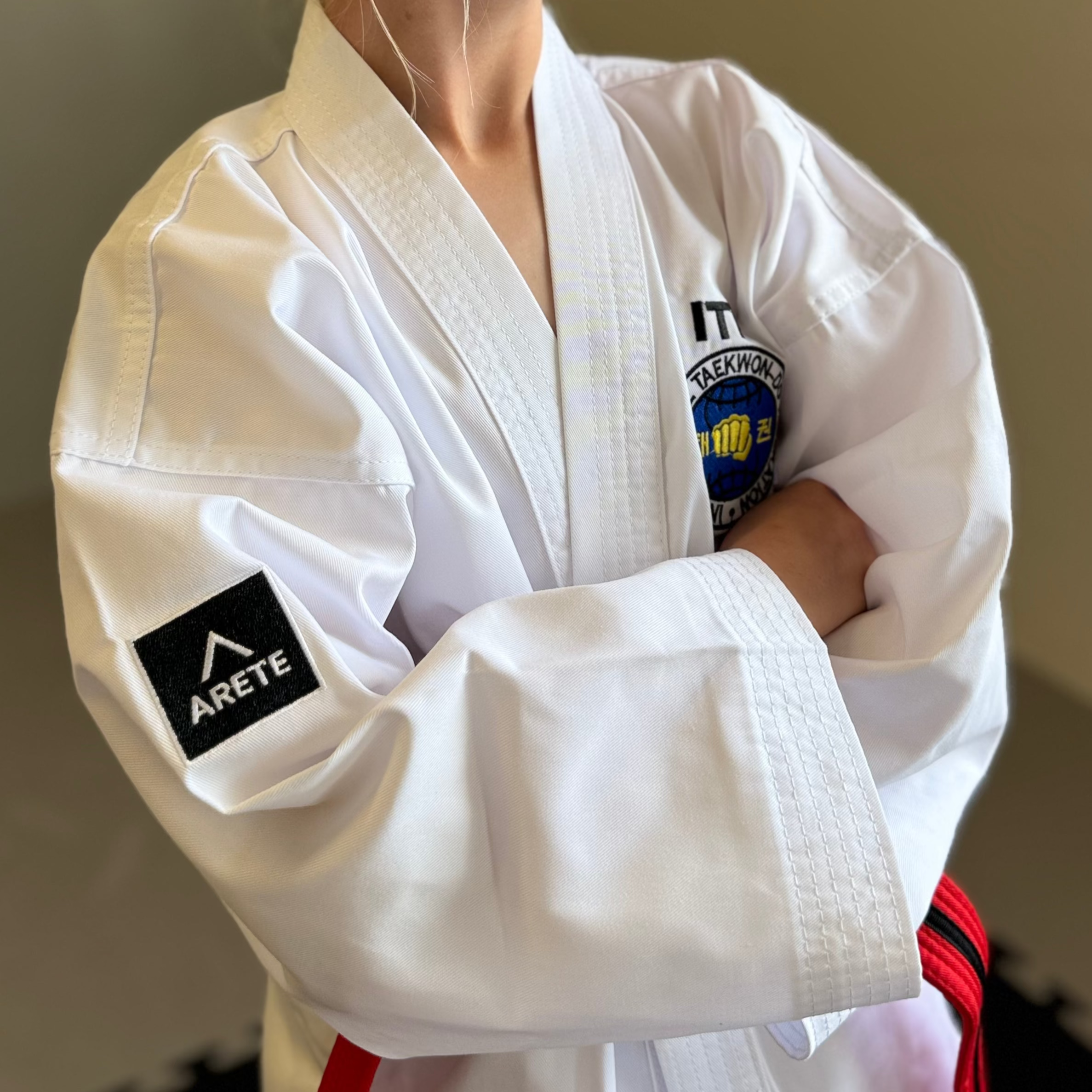 Person wearing a white martial arts uniform with visible branding, standing against a neutral background.