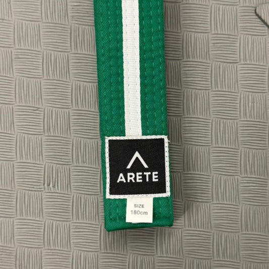 Green martial arts belt with white stripe on a textured gray background