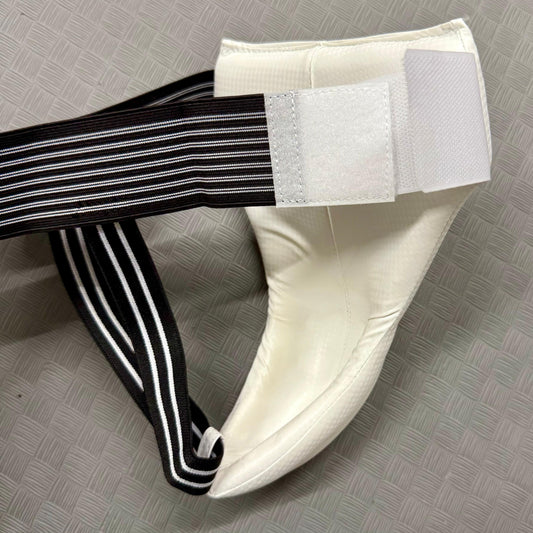 White groin guard black and white striped strap on a grey textured surface