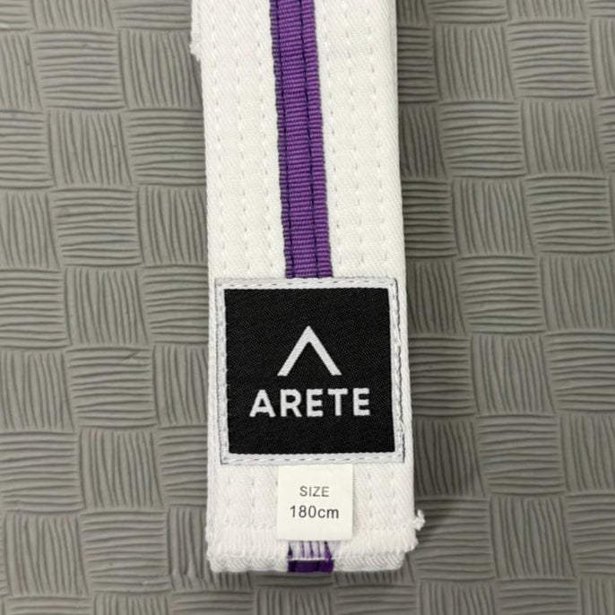 White belt with purple stripe on a textured gray surface, featuring the Arete brand logo.