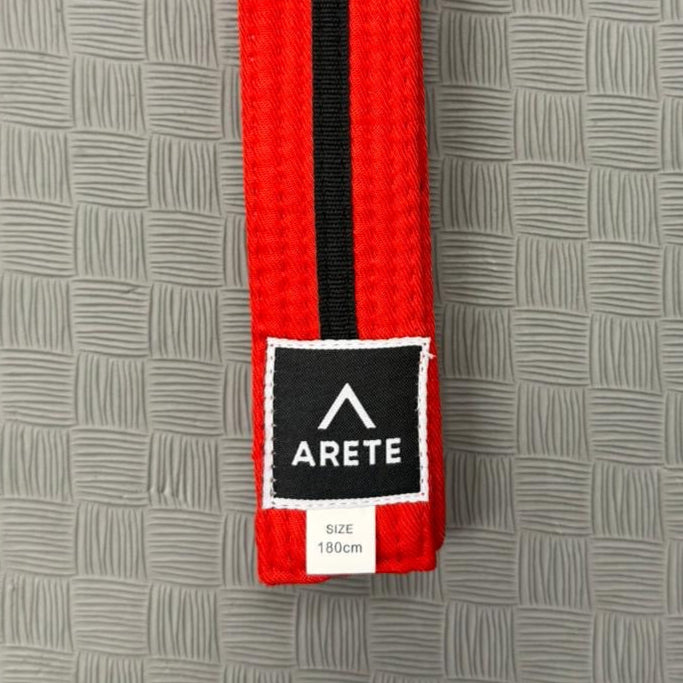 Red and black belt with Arete logo on a gray textured background