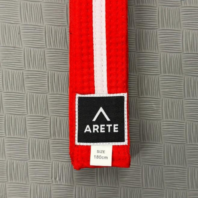 Red belt with a black and white logo on a textured gray background