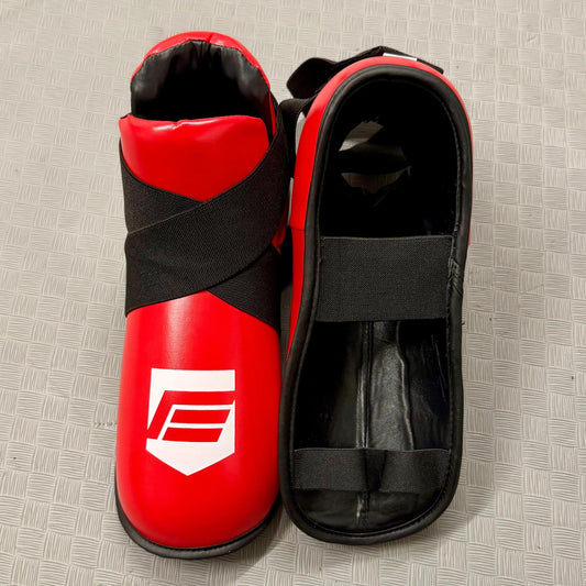Red and black foot protection gear on a textured grey surface