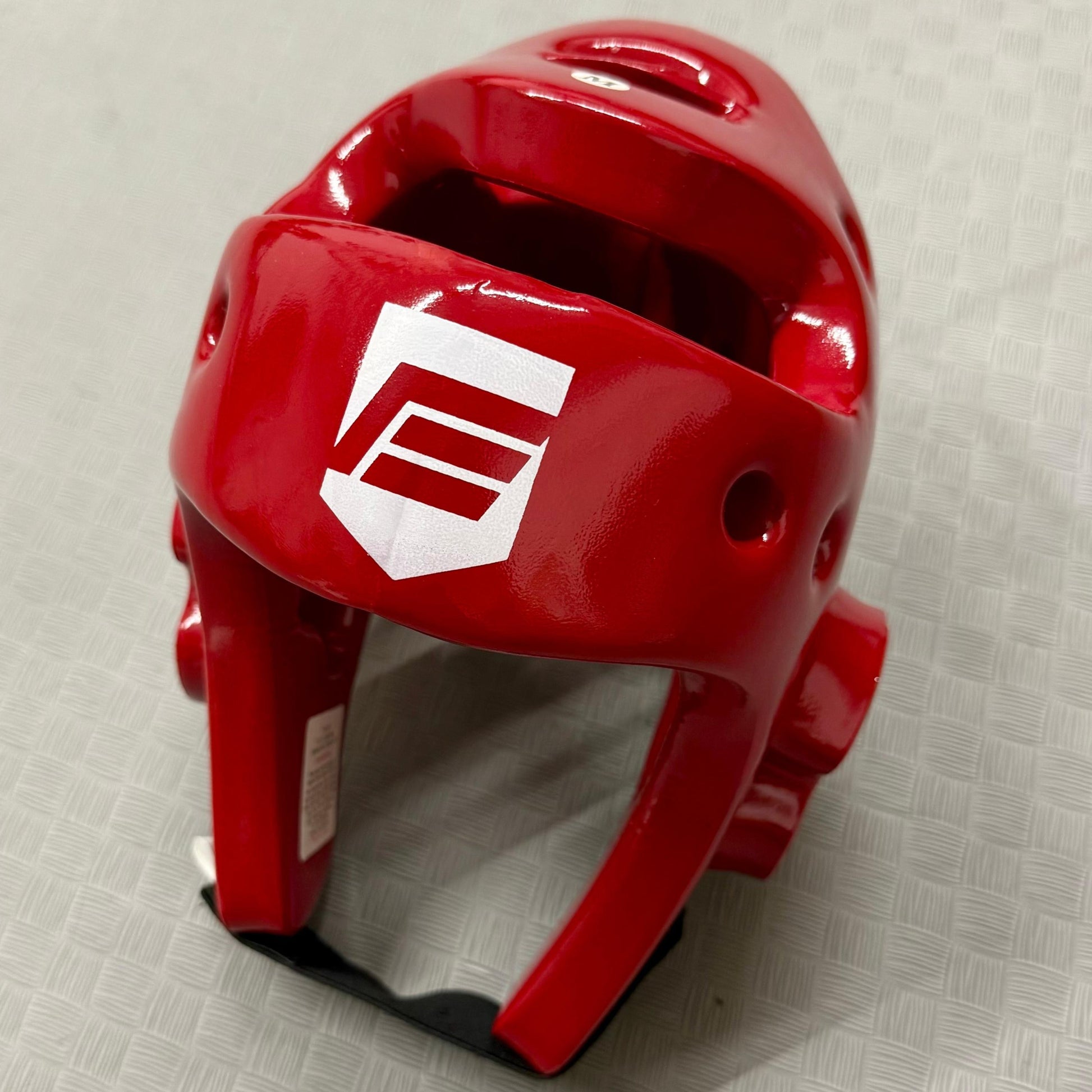 Red helmet with a logo on a textured grey surface