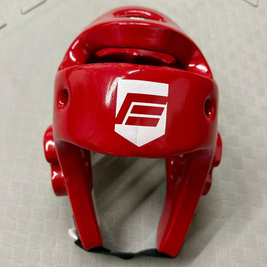 Red protective headgear with a logo on a grey floor